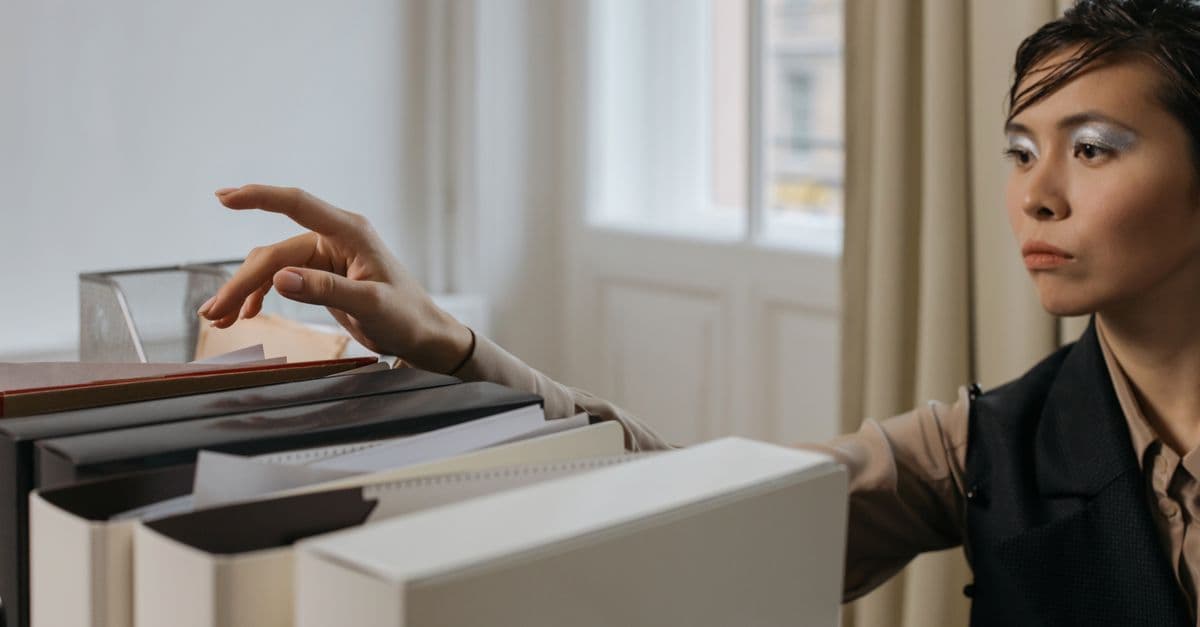 A stylish woman organizes documents in a modern office setting.