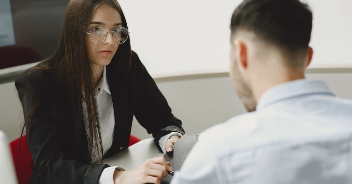 Two professionals engage in a serious business meeting at a modern office setting.