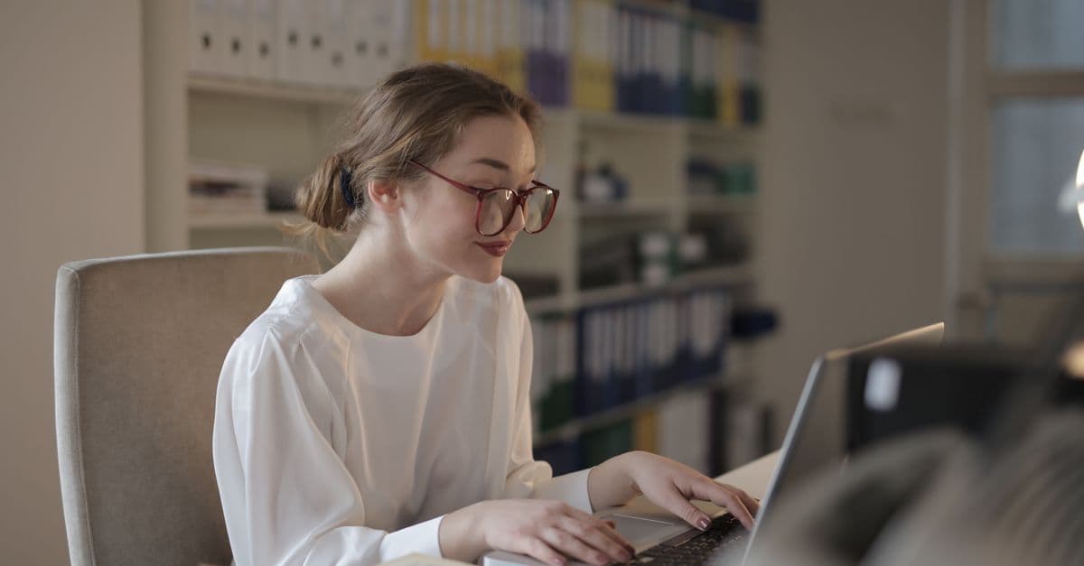 A professional woman concentrating on her laptop at a modern office desk.