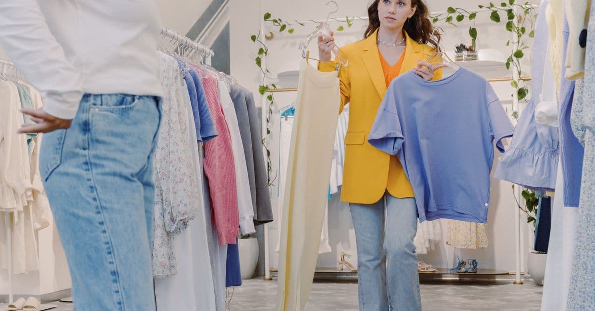 Woman shopping in boutique holding clothes for fitting in a modern fashion store.
