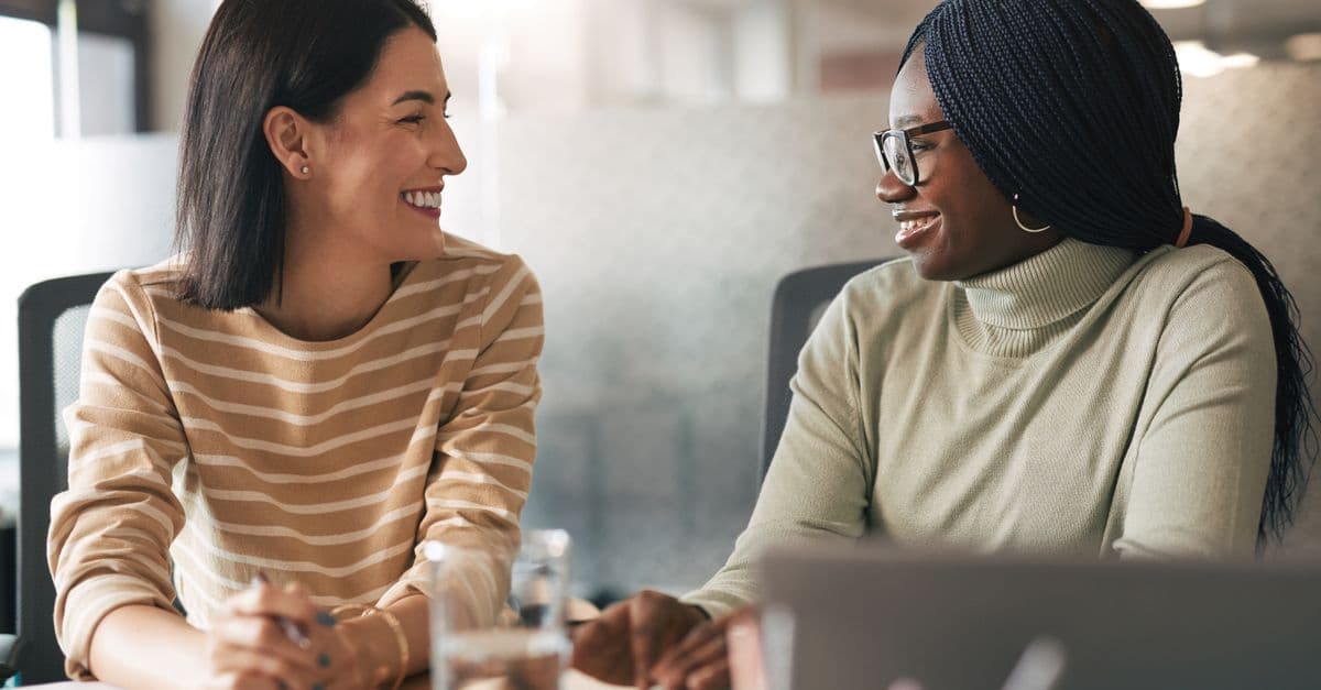 Two diverse colleagues share ideas in a modern office setting during a collaborative meeting.